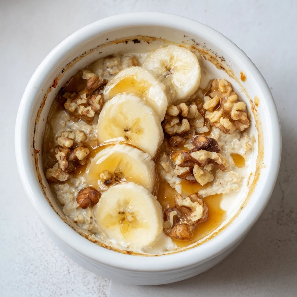 Individual ramekin of Baked Oats, with perfectly caramelized banana slices, ready to savor for breakfast.