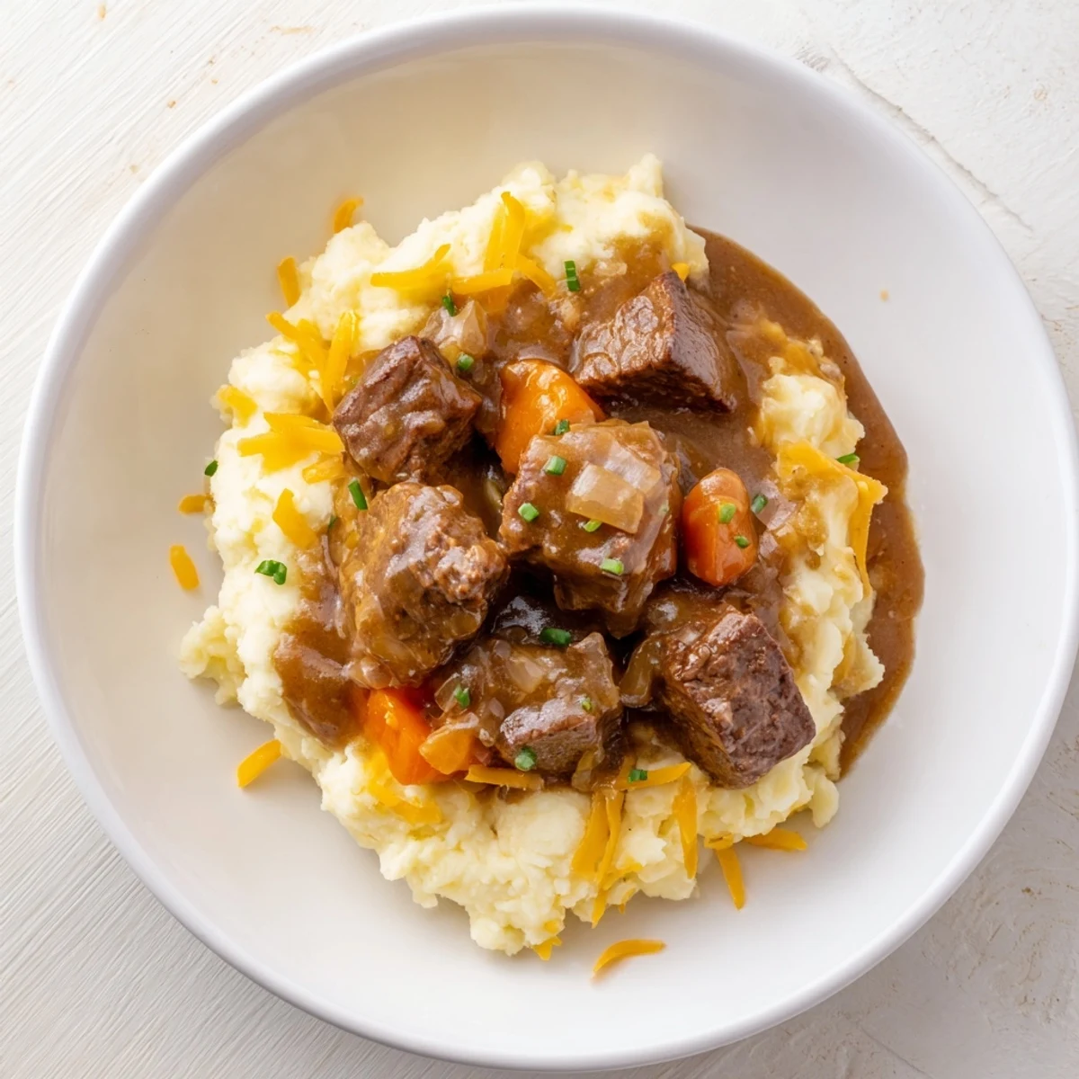 Steaming bowl of Fall Apple Cider Stew Mash, creamy potatoes topped with savory beef and vibrant chives.
