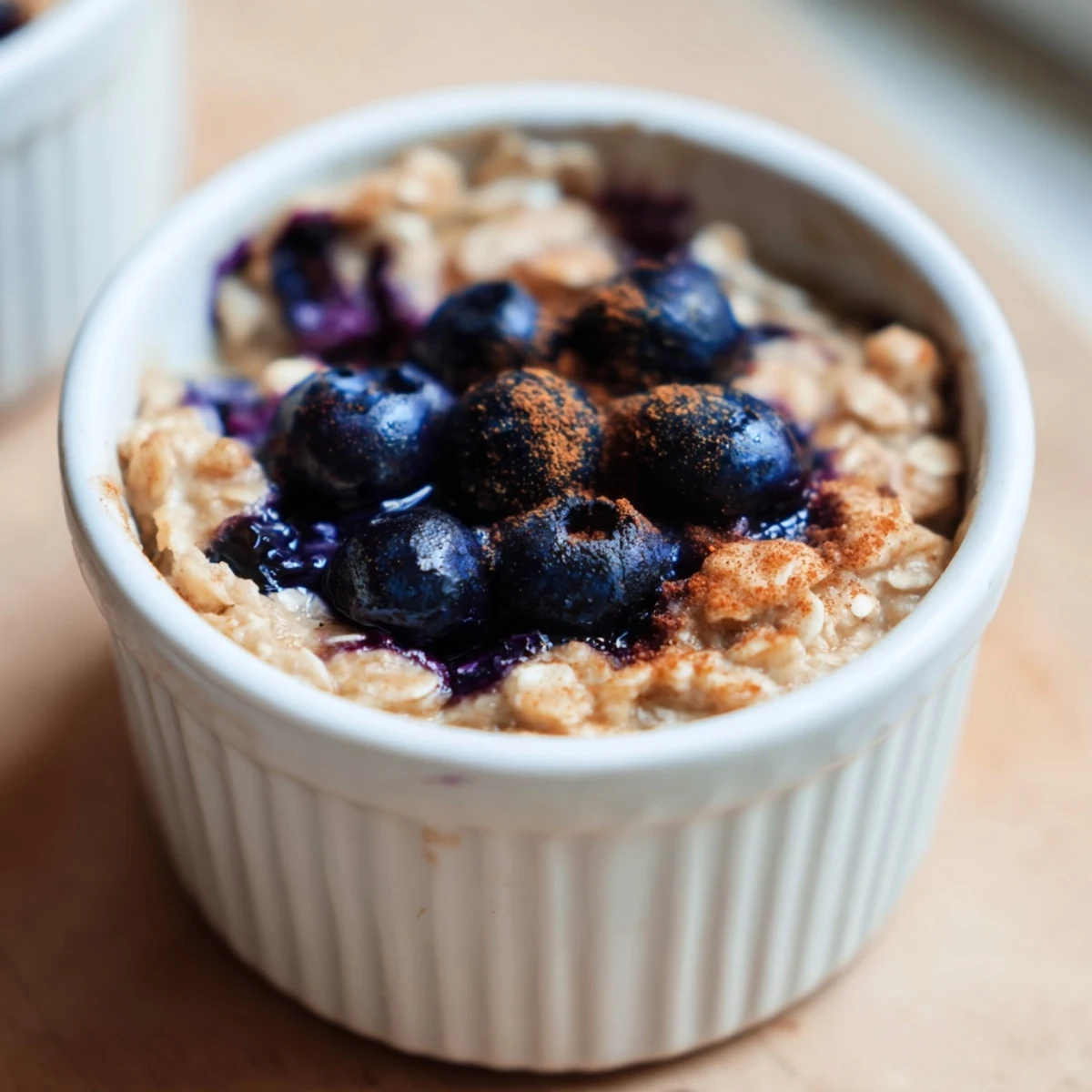 Fluffy Blueberry Baked Oats topped with fresh blueberries, served warm with a drizzle of syrup.