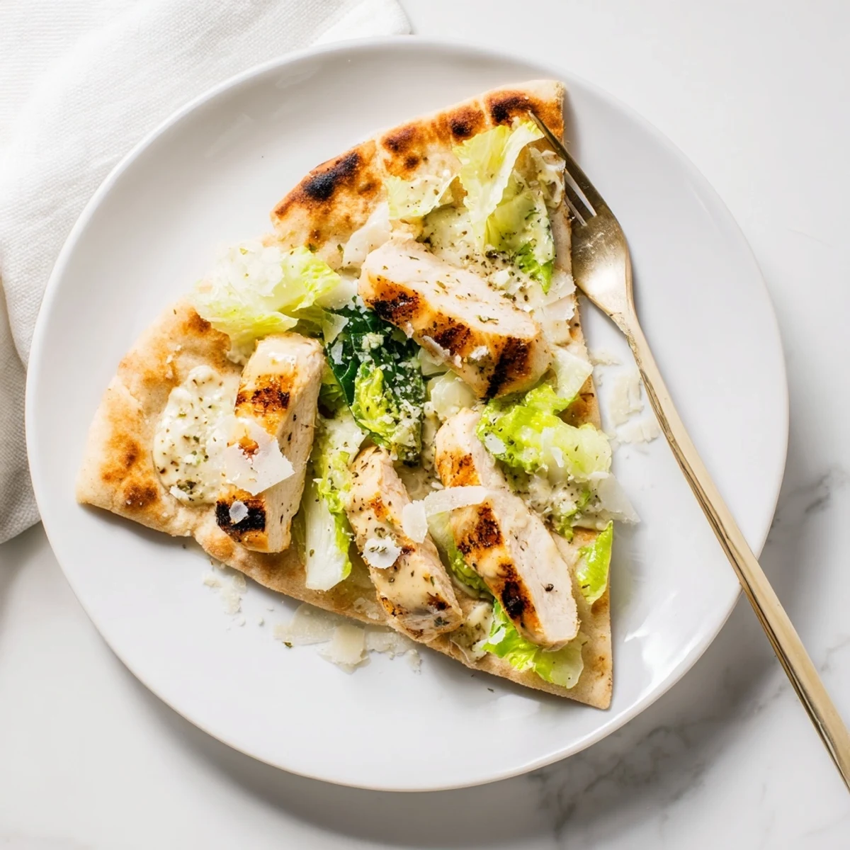 A serving of Chicken Caesar Flatbread topped with grilled chicken, fresh romaine, and parmesan, drizzled with creamy Caesar dressing.