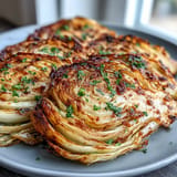 Crispy-edged cabbage steaks baked to perfection, drizzled with olive oil, garlic, and a bright splash of fresh lemon juice.  