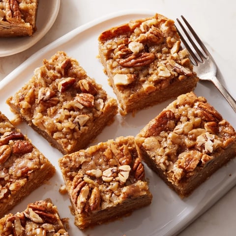 Chewy maple pecan blondies with golden edges, topped with toasted pecans.