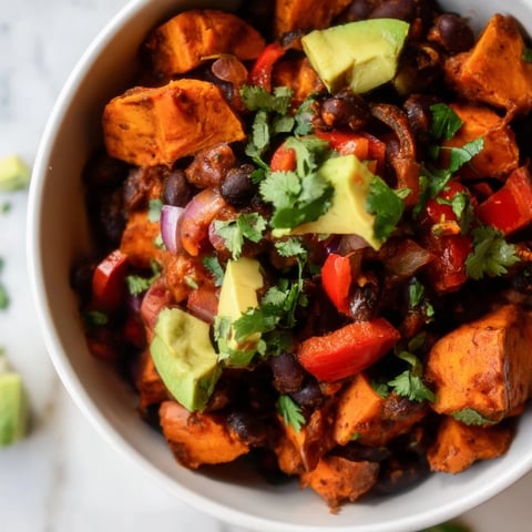 Steaming bowl of Sweet Potato & Black Bean Chili, garnished with cilantro, ready to eat.