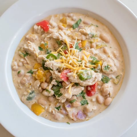Steaming bowl of creamy white chicken chili with beans, garnished with fresh cilantro and green onions.