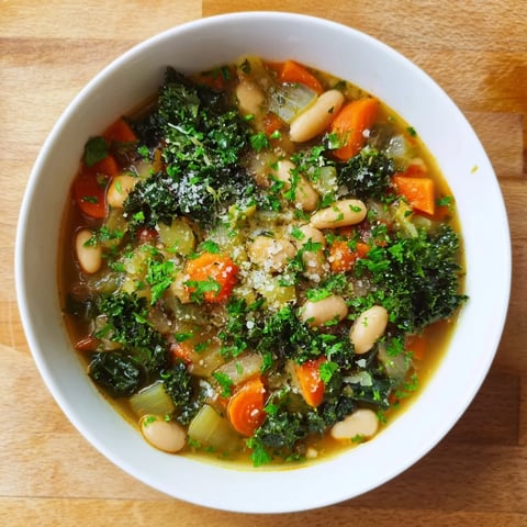 Steaming bowl of Italian Bean & Kale Stew, a vibrant, savory vegetarian delight on the table.