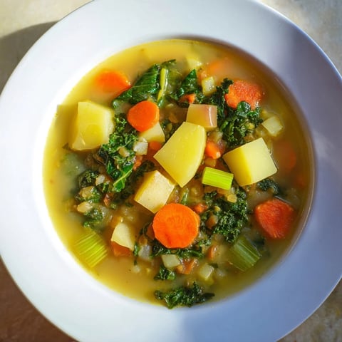Steaming bowl of Vegetarian Potato-Kale Soup, garnished, ready to warm you on a cold day.
