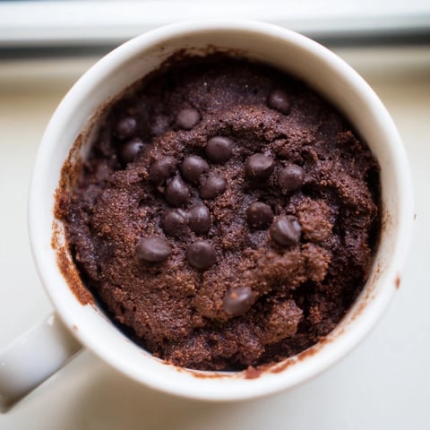 Steaming, freshly microwaved mug cake, perfect single-serve dessert with optional chocolate chips.