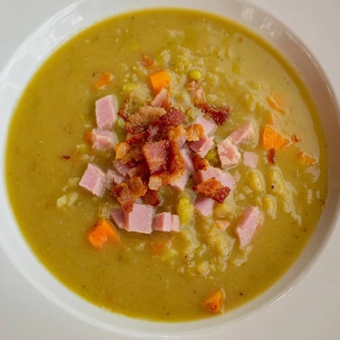 Steaming bowl of Split Pea Soup with canned ham, garnished with crispy bacon, ready to enjoy.