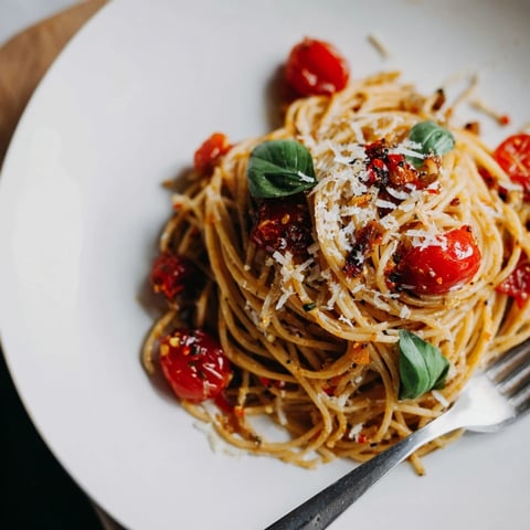 Steaming bowl of Lazy-Girl Pasta, glistening with tomatoes, Parmesan, and a touch of basil.