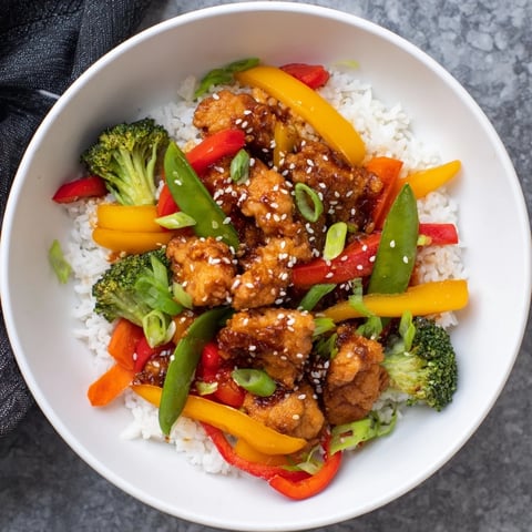 Golden chicken stir-fry with colorful veggies and fluffy rice, ready to eat and enjoy.