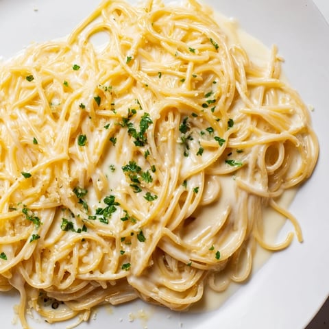 A steaming bowl of Creamy Three-Cheese Spaghetti, coated in a luscious, melted cheese sauce.