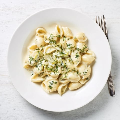 A close-up shot of creamy Pickle Mac and Cheese, garnished with fresh dill, ready to eat.