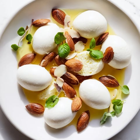 The Polished Pebble appetizer showcases creamy cheeses and toasted almonds arranged like a playful stream.