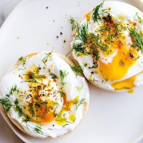 Çılbır Eggs Benedict: creamy yogurt base beneath perfectly poached eggs, drizzled with spiced butter.