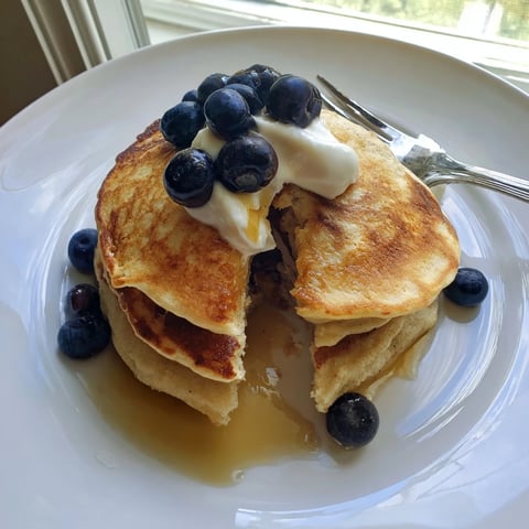 A stack of fluffy Cottage Cheese Pancakes drizzled with maple syrup and topped with fresh berries.  