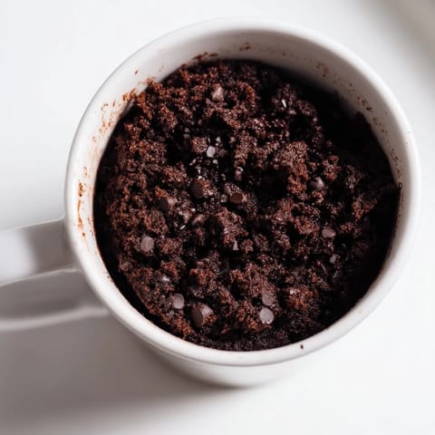 A fluffy, chocolatey microwaved mug cake, ready to devour, a quick sweet treat in a mug.