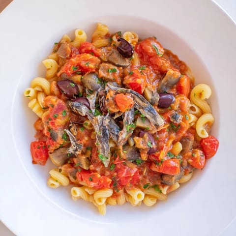 A close-up of Puttanesca Ditalini, showing al dente pasta with a vibrant sauce and fresh parsley.