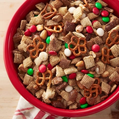 Golden-baked Holiday Mix, a delicious snack with pretzels, peanuts, and colorful candies for your gathering.