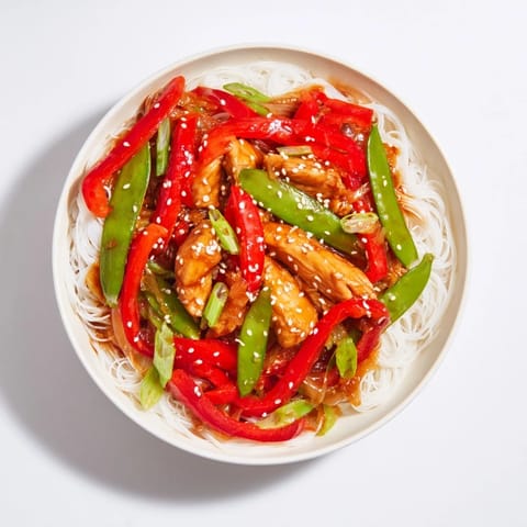 A steaming bowl of Mongolian Chicken shows beautifully glazed chicken and tender noodles, ready to eat.