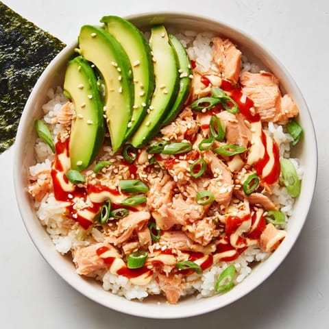 Flaky salmon mixed into warm rice with green onions and sesame seeds in an Emily Mariko Salmon Rice Bowl.