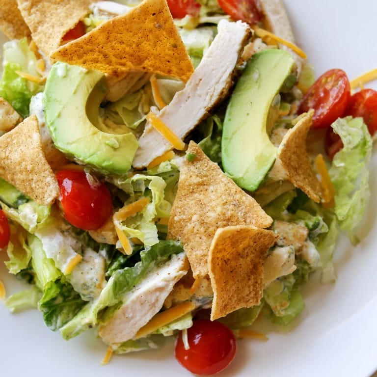 Crunchy Taco Chicken Salad features sliced taco-seasoned chicken, veggies, and creamy lime dressing, served with crunchy shell pieces.
