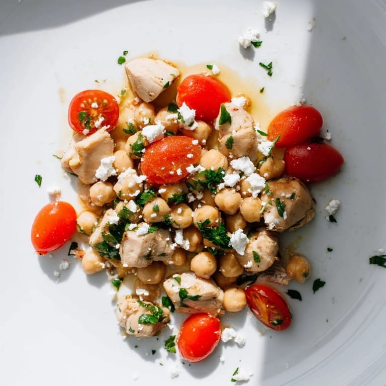 A vibrant Mediterranean Chickpea Chicken Salad tossed with chickpeas, cherry tomatoes, red onion, parsley, and crumbled feta, ready for a healthy lunch.