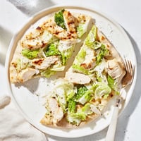 Grilled chicken and crisp romaine lettuce layered over golden flatbread with creamy Caesar dressing and parmesan, perfect for a light lunch.  