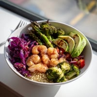 Fluffy quinoa and succulent shrimp top a colorful Detox Buddha Bowl with crisp broccoli, red cabbage, and creamy avocado.